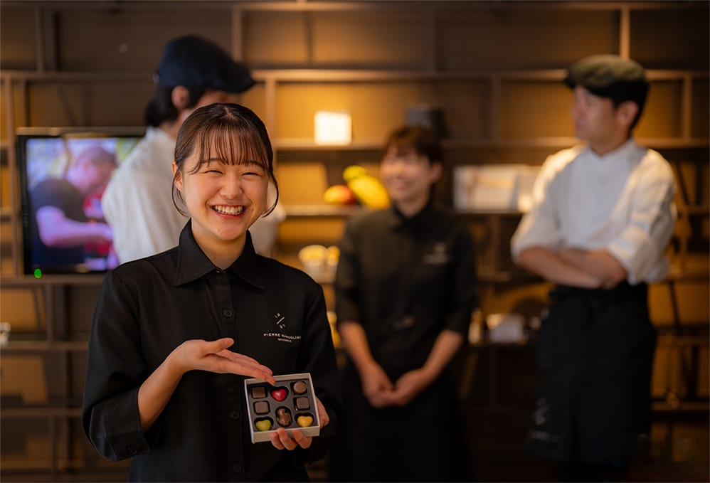 チョコレートを持って笑顔で説明するスタッフの女性の写真